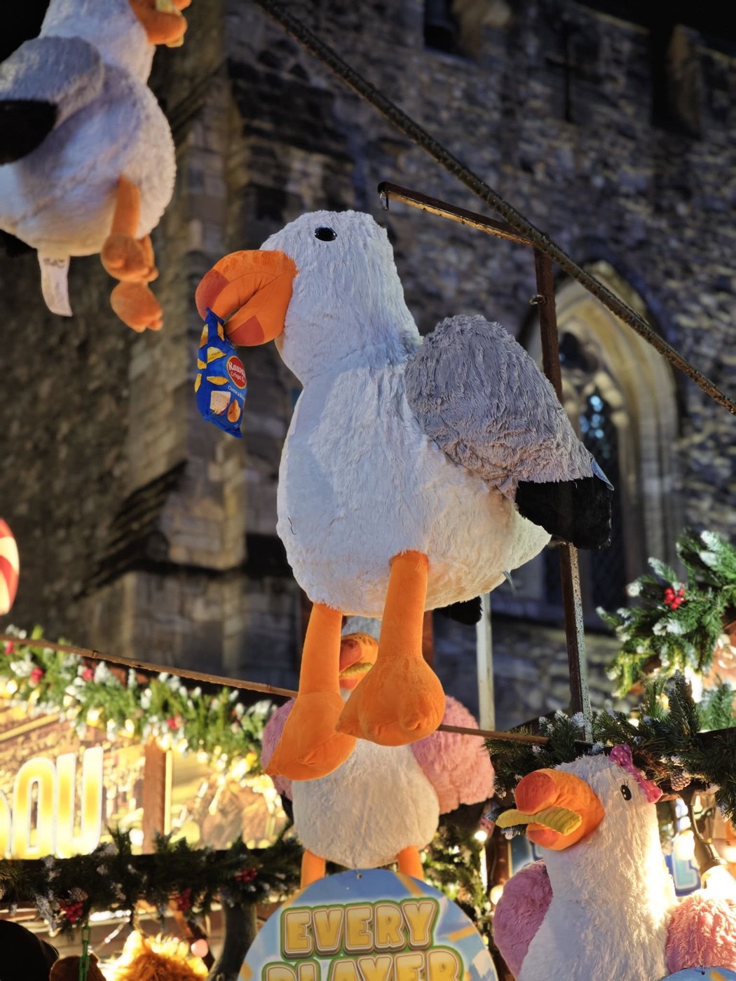 A fluffy seagull soft toy hanging as a prize on a carnival stall